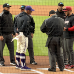 Northwestern coach Ben Greenpan and Indiana coach Jeff Mercer meet with the umpires at home plate at Wrigley Field